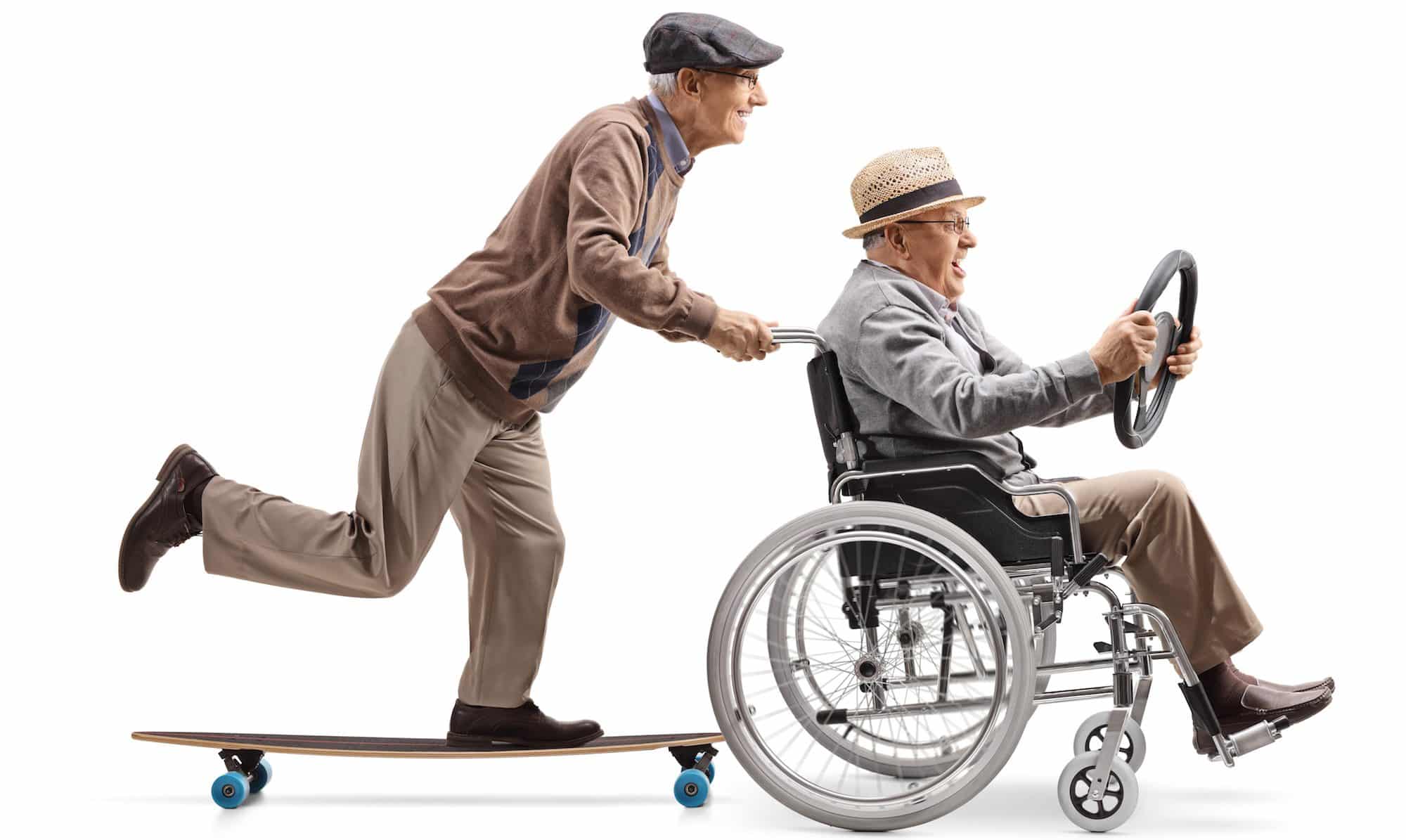 Elderly man riding a longboard and pushing a man holding a steering wheel and sitting in a wheelchair